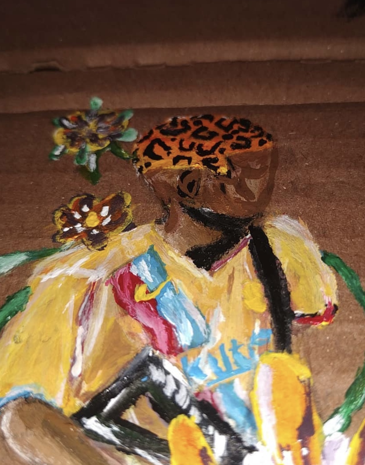 Detalhe do rosto e da flor pintados sobre o papelão