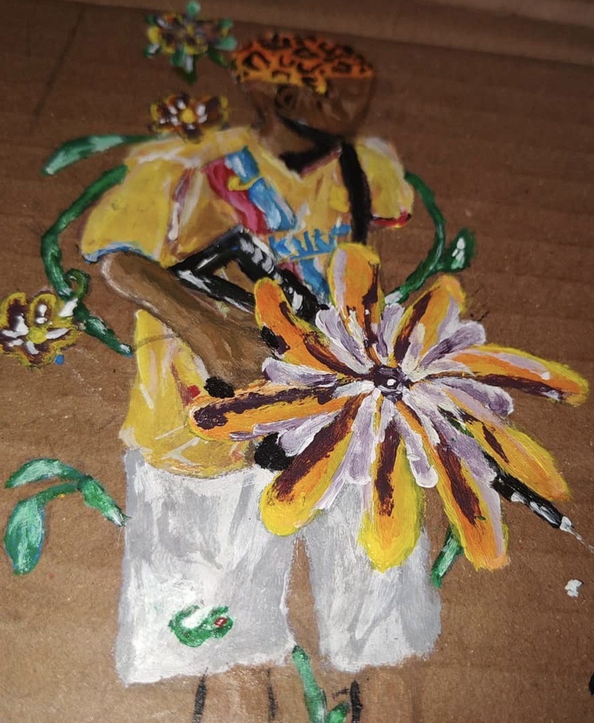 Personagem de cabelo com estampa de onça e blusa amarela segurando uma flor e uma arma, sobre papelão