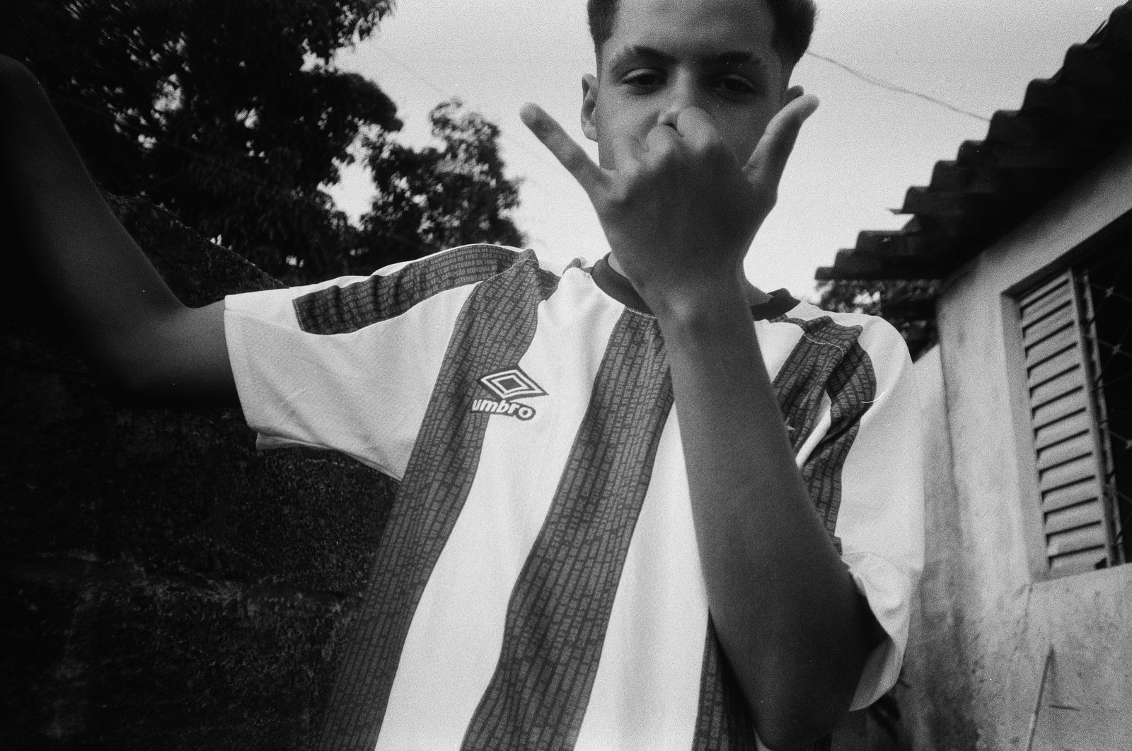 Jovem de camisa listrada fazendo um gesto com a mão em frente ao rosto